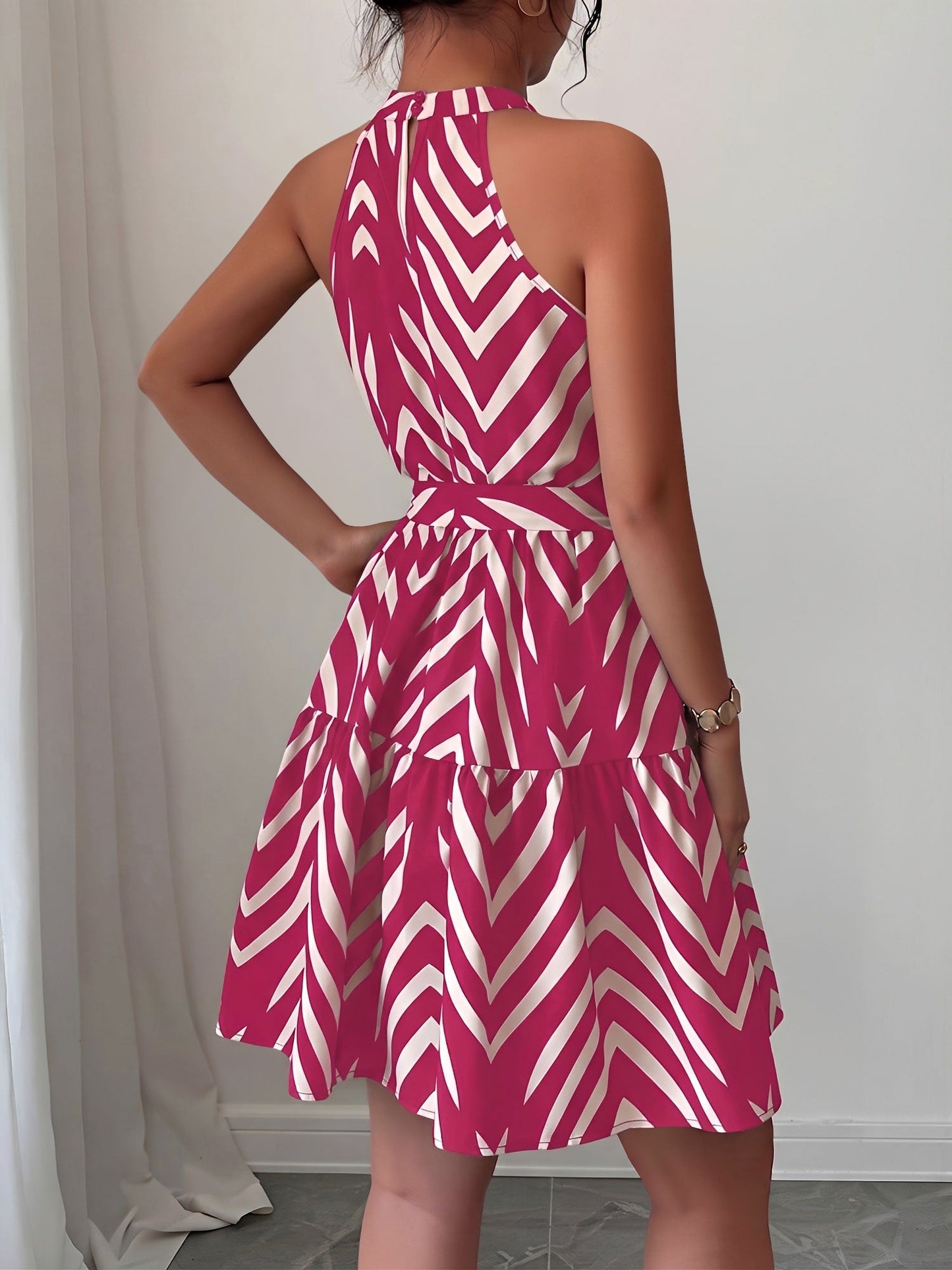 Rose Red - Woman wearing a geometric patterned halter-neck mini dress with a tie waist and tiered skirt.