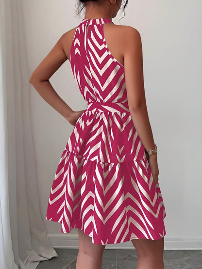 Rose Red - Woman wearing a geometric patterned halter-neck mini dress with a tie waist and tiered skirt.