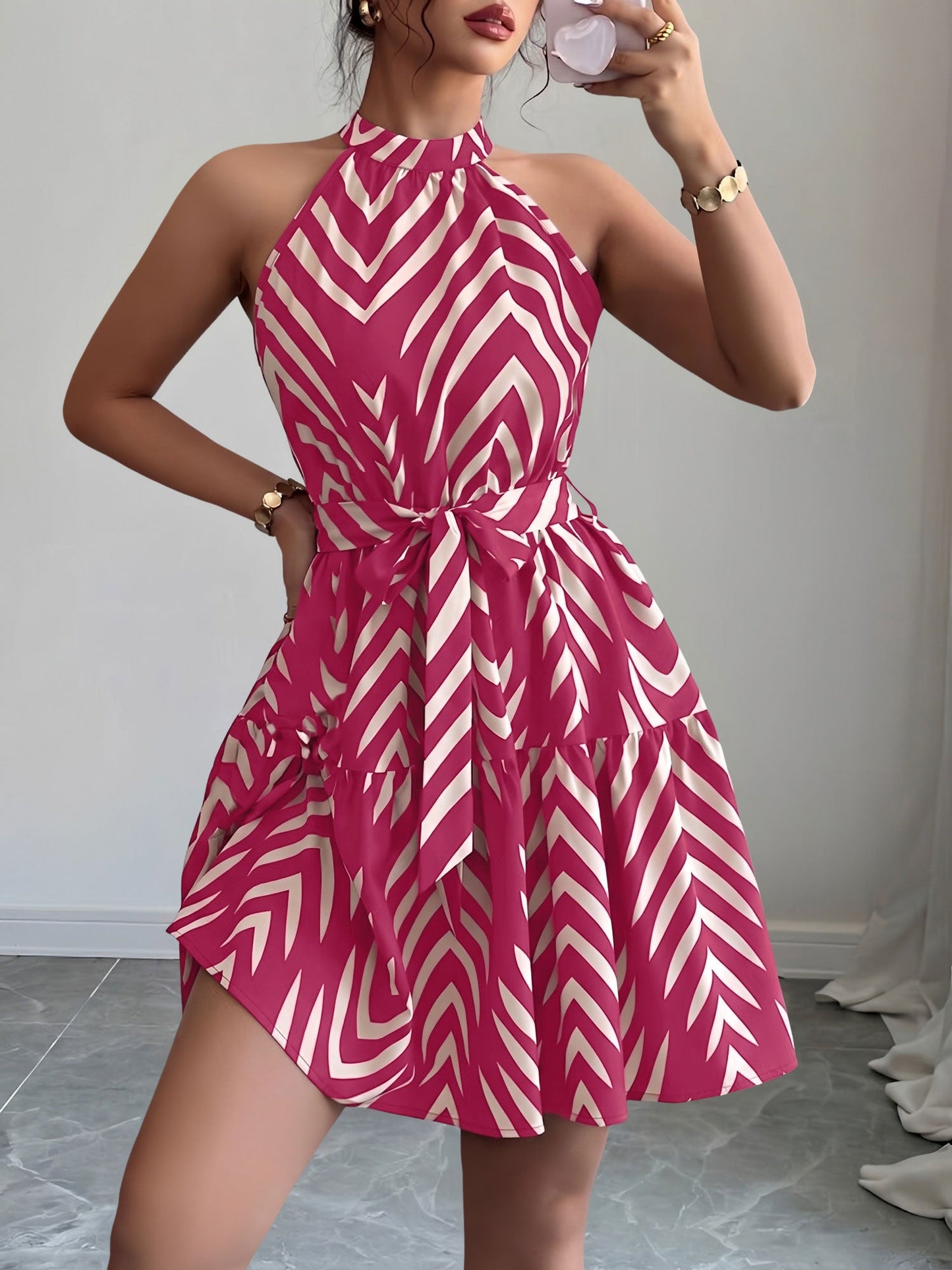 Rose Red - Woman wearing a geometric patterned halter-neck mini dress with a tie waist and tiered skirt.