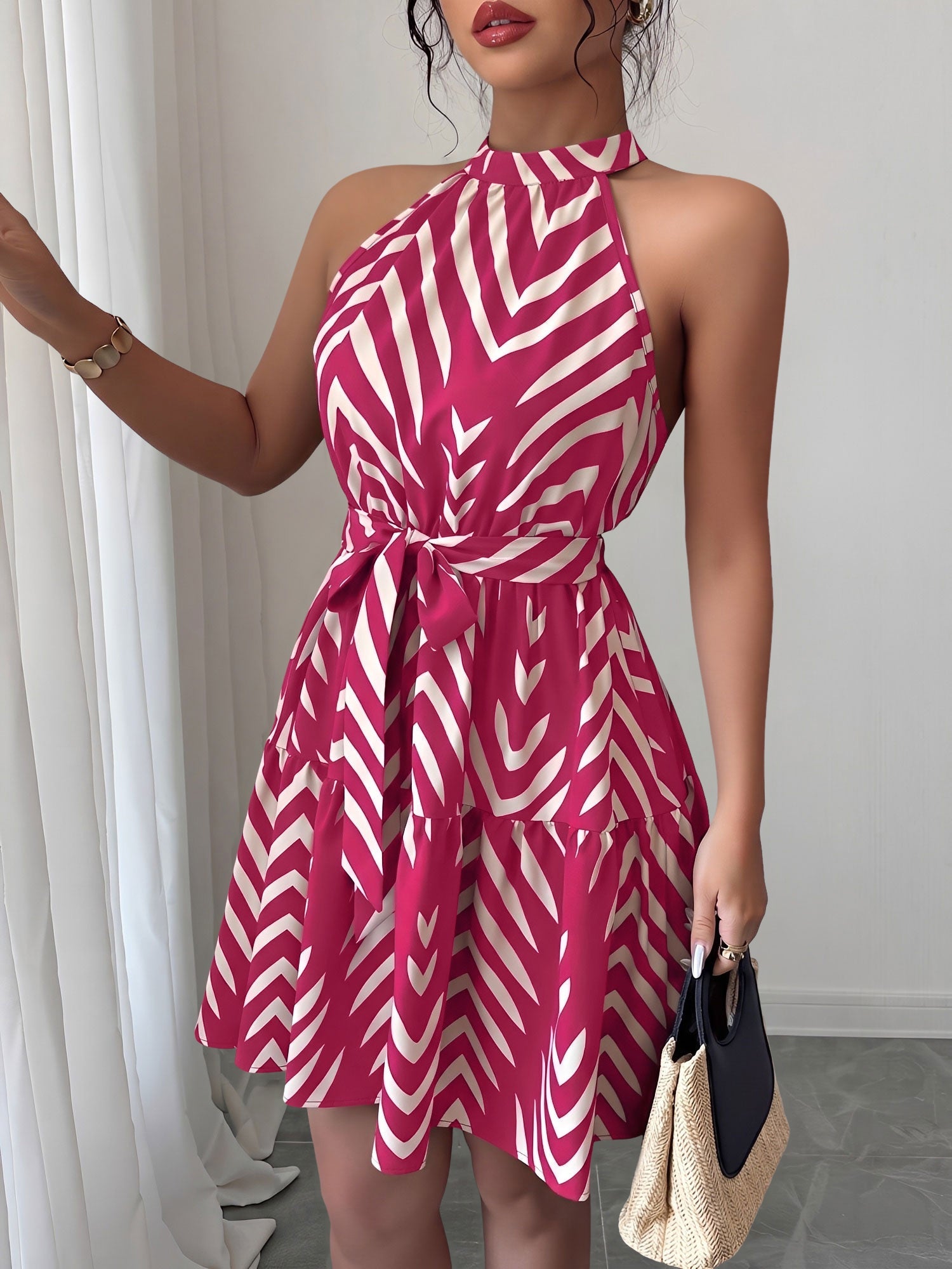 Rose Red - Woman wearing a geometric patterned halter-neck mini dress with a tie waist and tiered skirt.