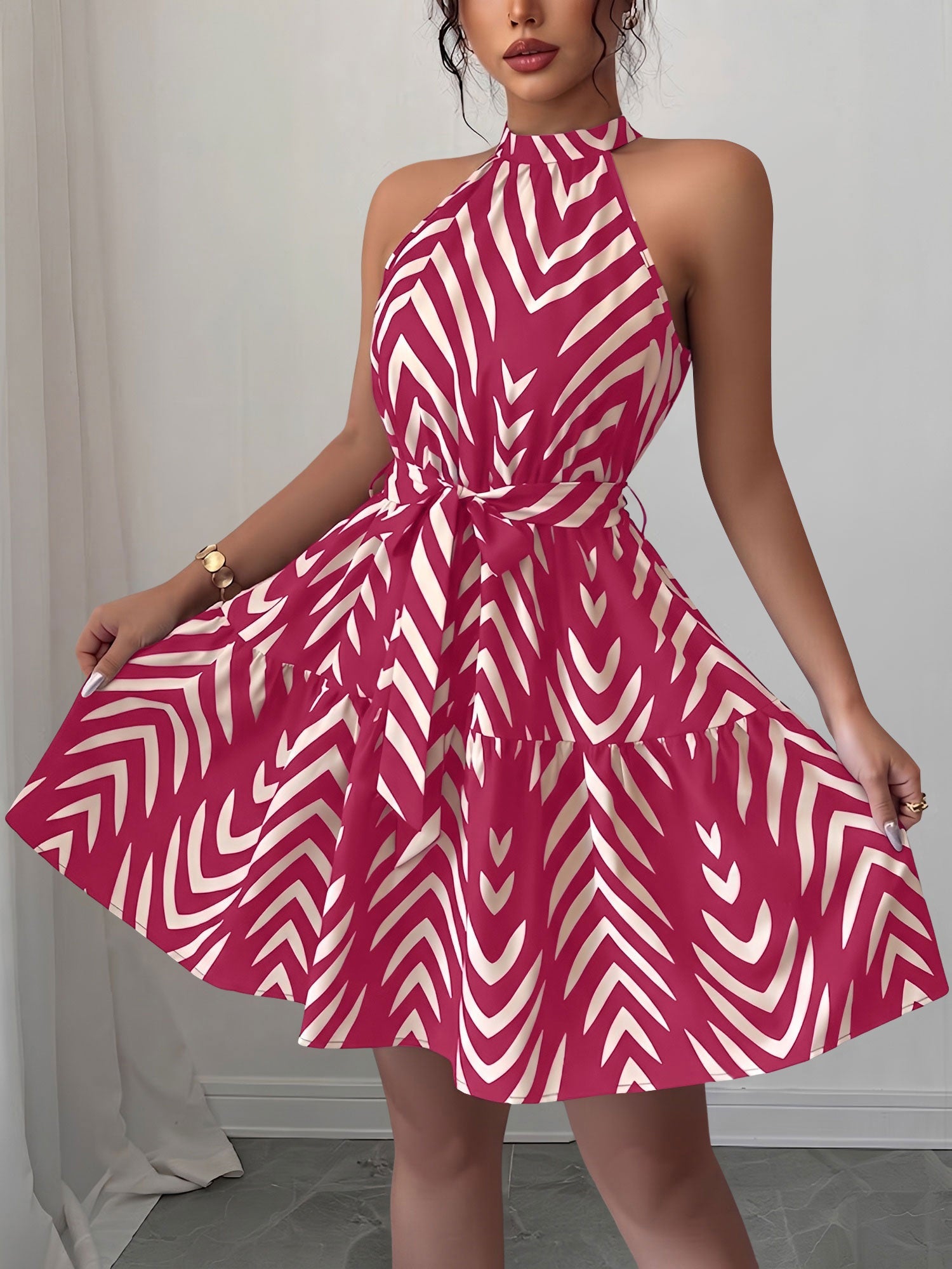 Rose Red - Woman wearing a geometric patterned halter-neck mini dress with a tie waist and tiered skirt.