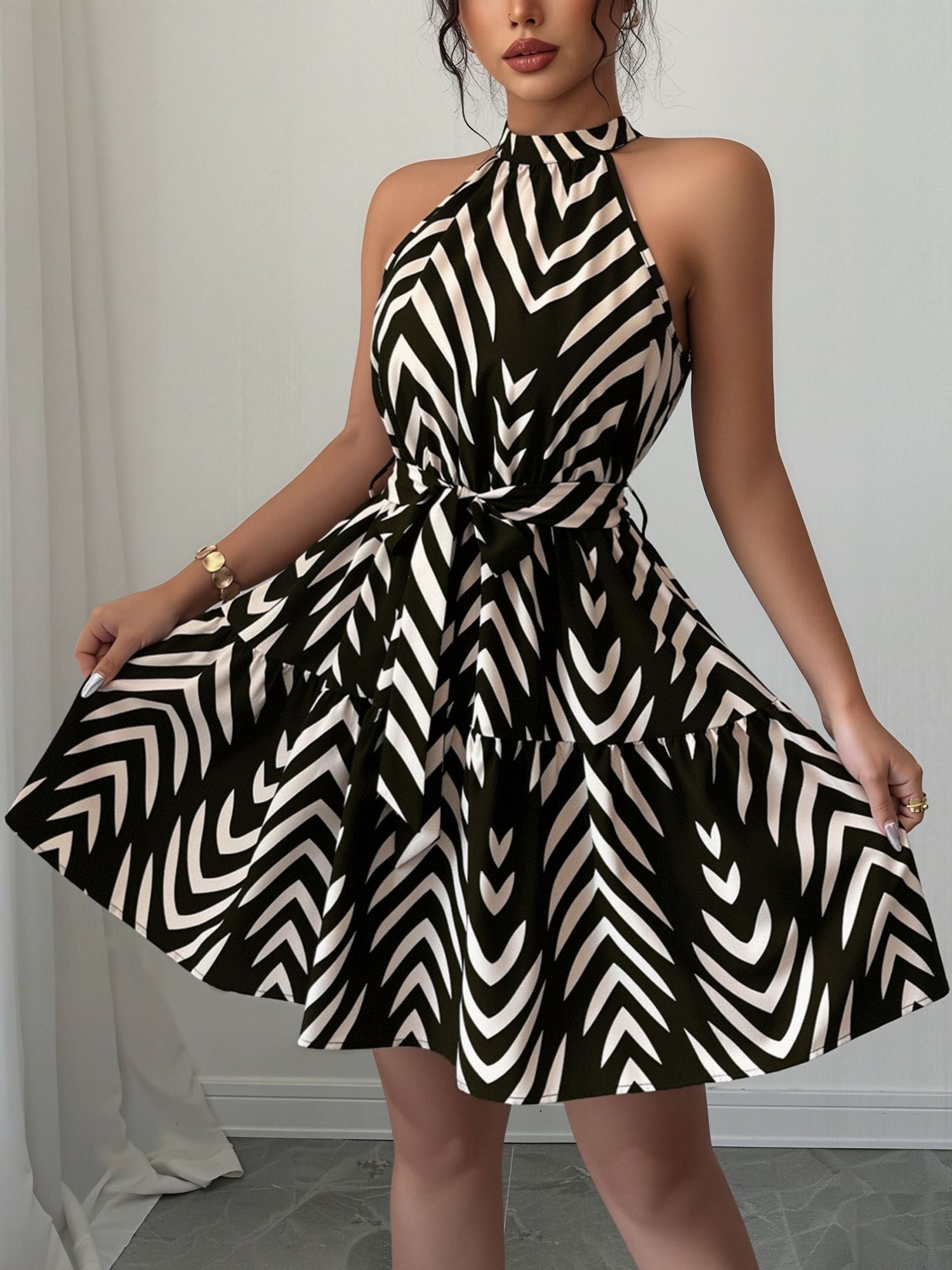 Black - Woman wearing a geometric patterned halter-neck mini dress with a tie waist and tiered skirt.