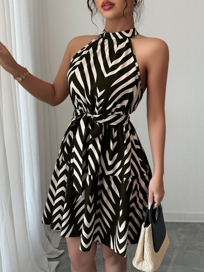 Black - Woman wearing a geometric patterned halter-neck mini dress with a tie waist and tiered skirt.