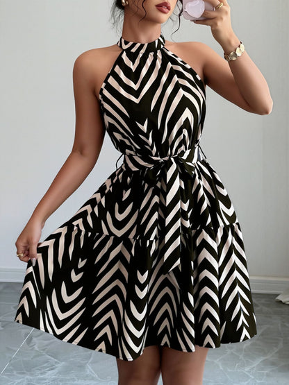 Black - Woman wearing a geometric patterned halter-neck mini dress with a tie waist and tiered skirt.