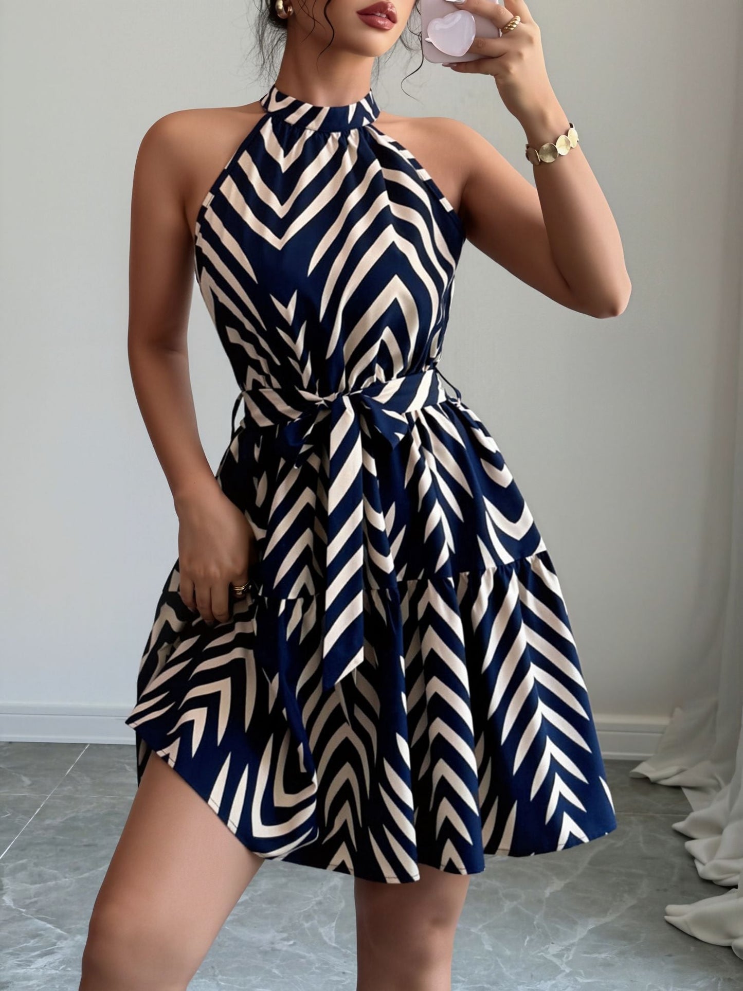 Blue - Woman wearing a geometric patterned halter-neck mini dress with a tie waist and tiered skirt.