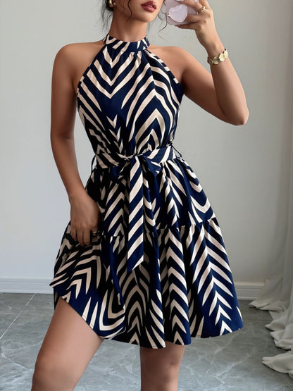 Blue - Woman wearing a geometric patterned halter-neck mini dress with a tie waist and tiered skirt.