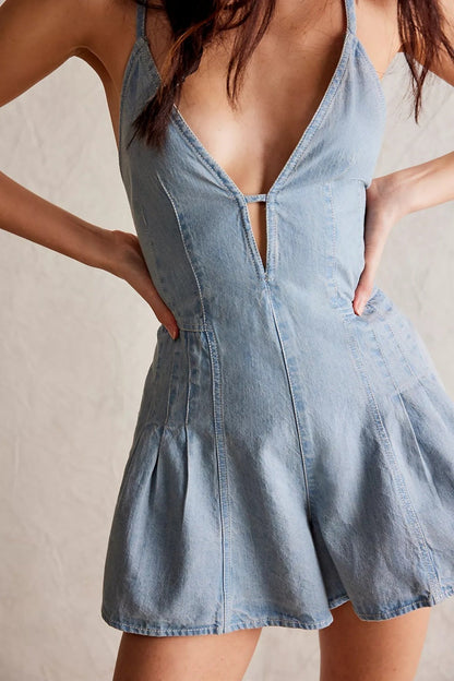 Light Blue - A woman modelling a light blue, structured mini dress featuring a deep plunging V-neckline, panelled bodice seams, and a pleated flared skirt.
