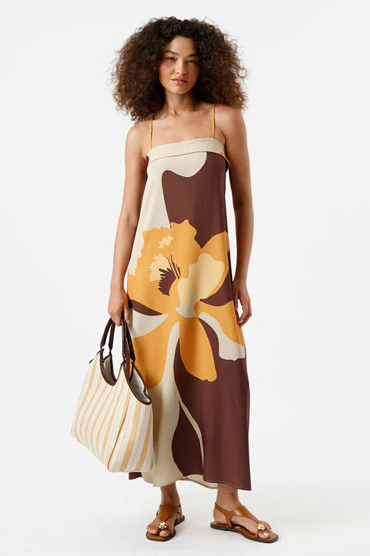 Multi - A woman wearing a long, relaxed-fit maxi dress with spaghetti straps and a fold-over straight neckline, featuring a large, bold abstract floral print in brown, mustard, and cream. She is holding a striped tote bag and wearing flat brown sandals against a white background.