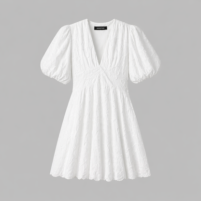 White - Woman wearing a textured jacquard A-line mini dress with a V-neckline and short puff sleeves against a grey background