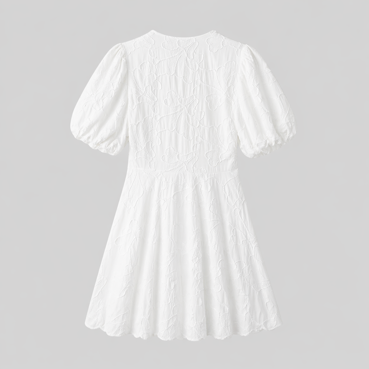 White - Woman wearing a textured jacquard A-line mini dress with a V-neckline and short puff sleeves against a grey background