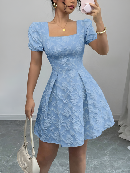 Sky Blue - Model wearing a textured floral jacquard mini dress with a square neckline, short puff sleeves, and a pleated A-line skirt