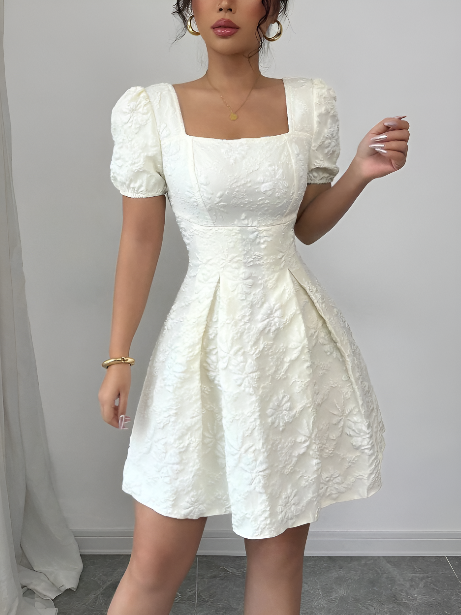 White - Model wearing a textured floral jacquard mini dress with a square neckline, short puff sleeves, and a pleated A-line skirt