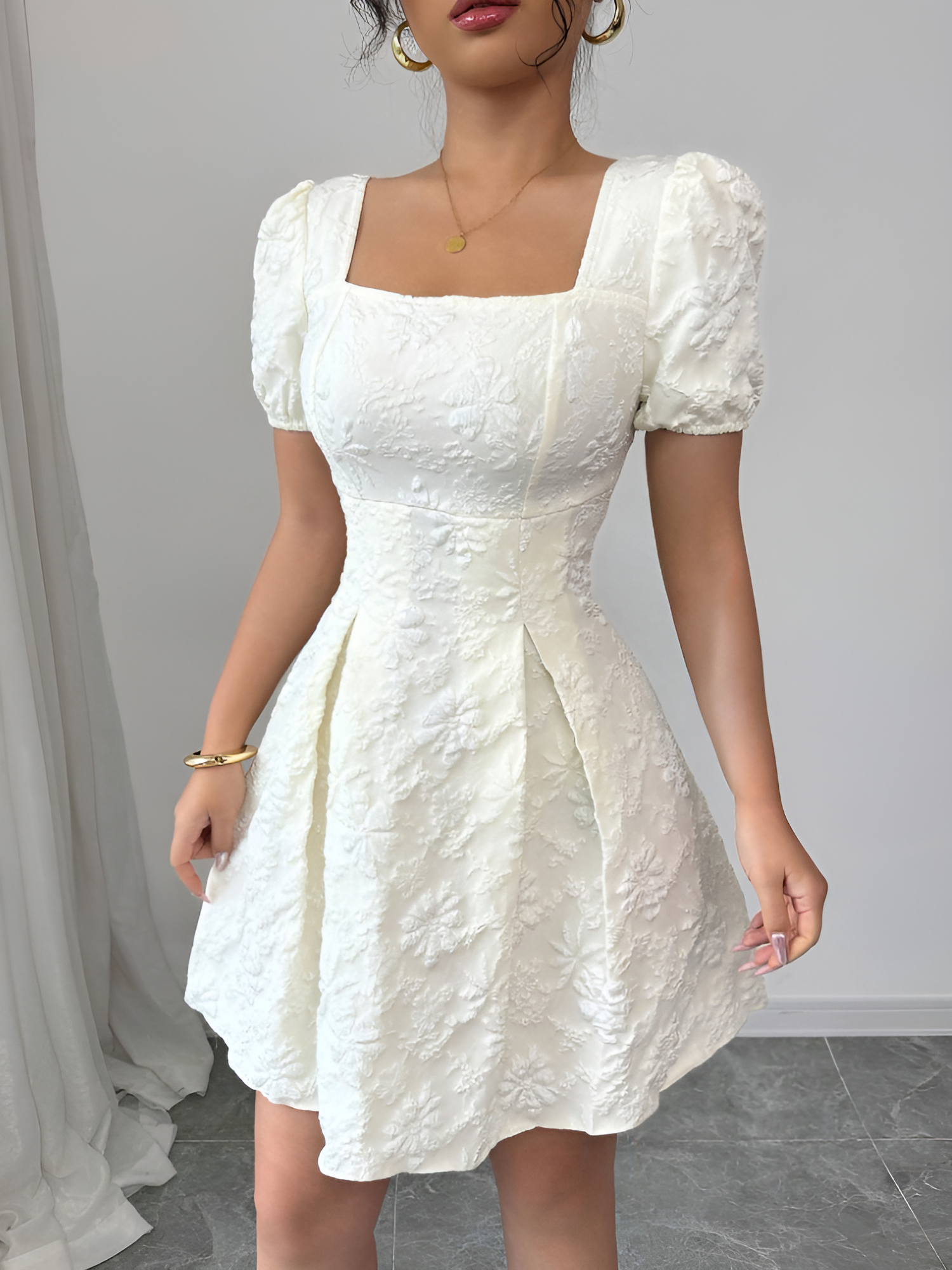 White - Model wearing a textured floral jacquard mini dress with a square neckline, short puff sleeves, and a pleated A-line skirt