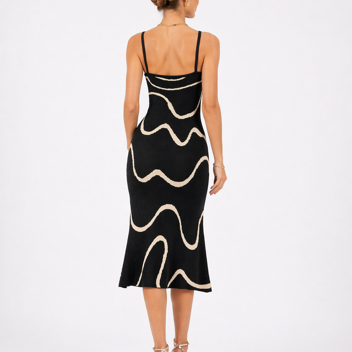 Black - Model wearing a sleeveless square-neck midi dress featuring an abstract wavy line pattern, styled with an evening clutch and heels.