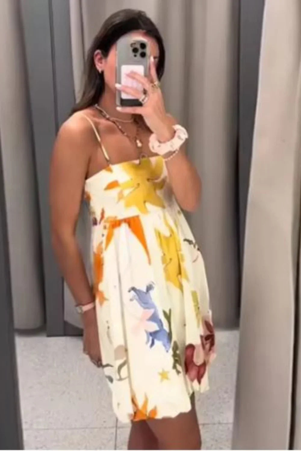 Woman wearing a white mini dress with a vibrant, large-scale abstract floral print, spaghetti straps, and a voluminous bubble hem.