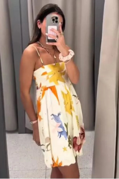 Woman wearing a white mini dress with a vibrant, large-scale abstract floral print, spaghetti straps, and a voluminous bubble hem.