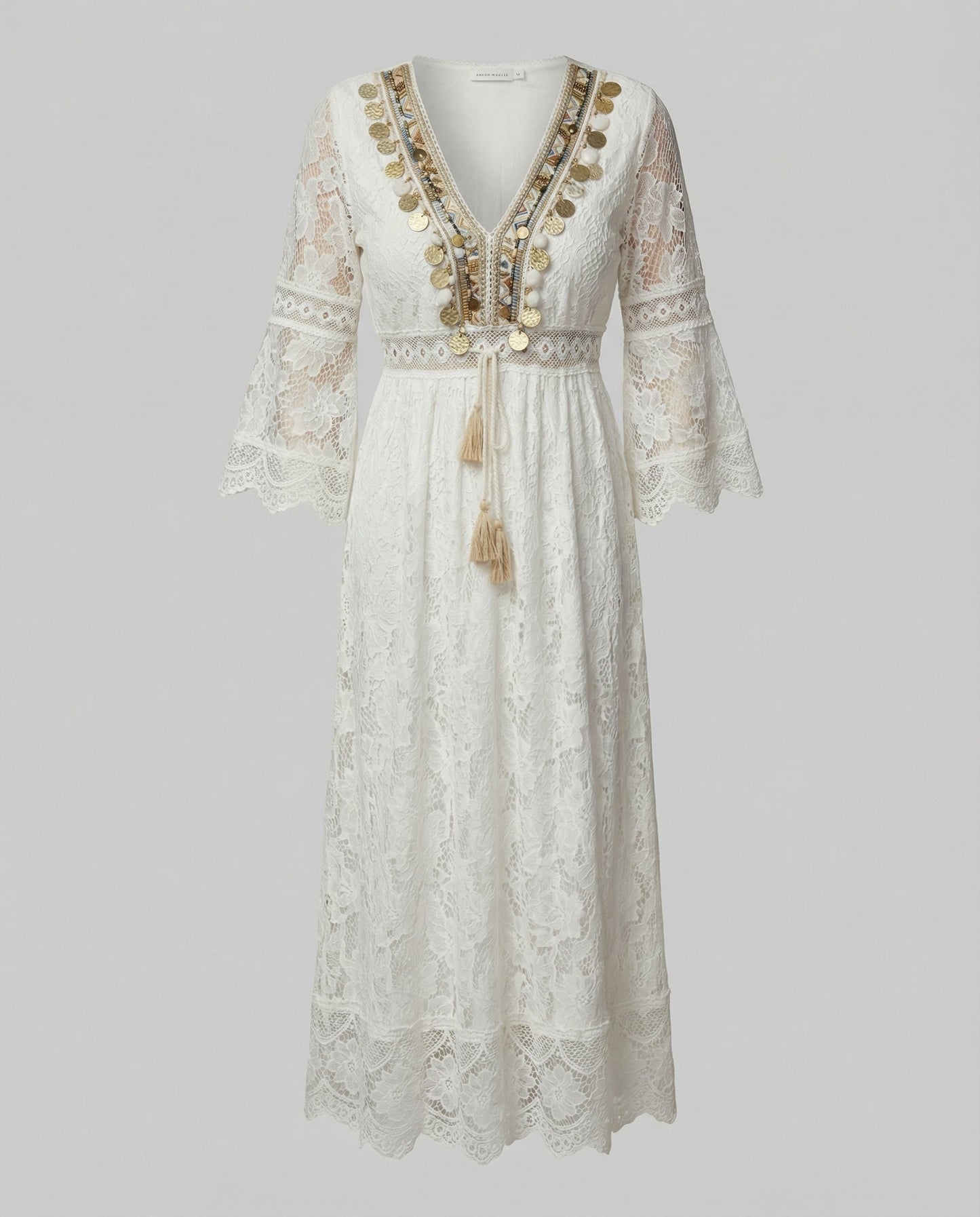 White - A woman wearing a bohemian lace maxi dress with a deep V-neckline, metallic embellishments, bell sleeves, and a tassel tie waist, holding a round woven bag.