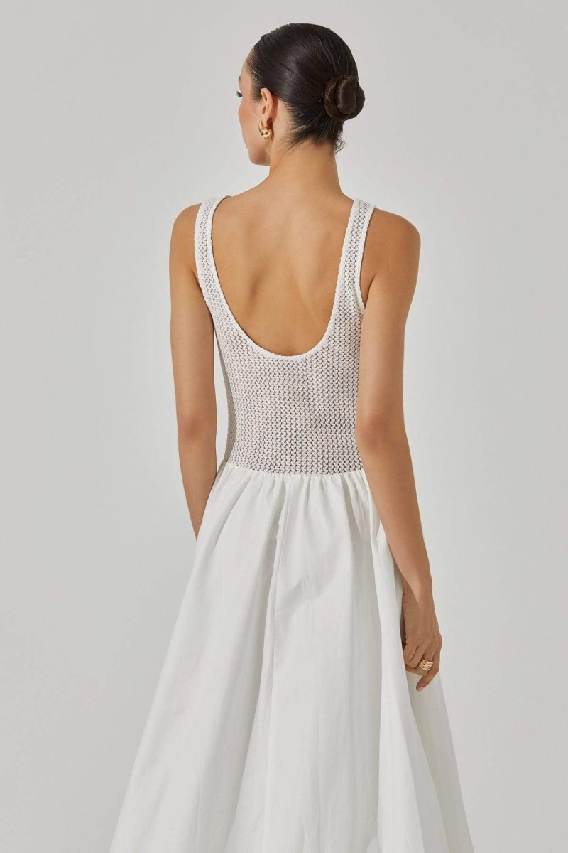 White - A woman stands against a white background wearing a sleeveless white midi dress. The dress has a textured open-knit tank-style bodice and a full, smooth A-line skirt that ends mid-calf.