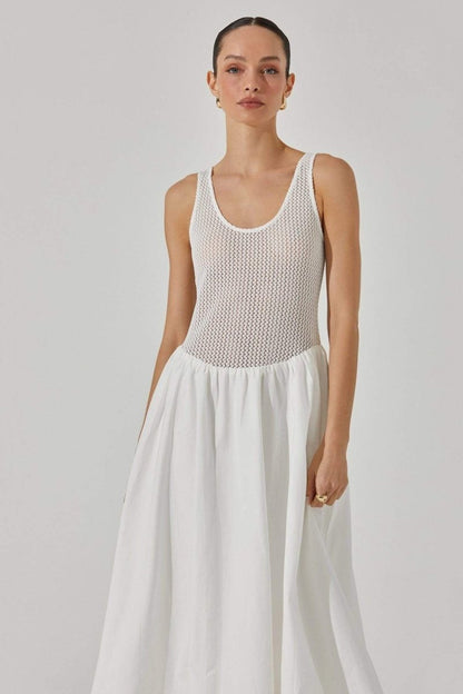 White - A woman stands against a white background wearing a sleeveless white midi dress. The dress has a textured open-knit tank-style bodice and a full, smooth A-line skirt that ends mid-calf.
