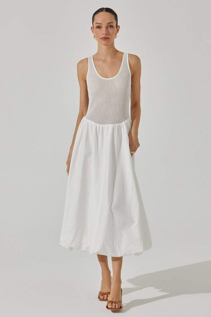 White - A woman stands against a white background wearing a sleeveless white midi dress. The dress has a textured open-knit tank-style bodice and a full, smooth A-line skirt that ends mid-calf.