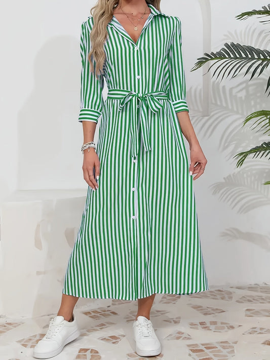 Woman wearing a striped poplin midi shirt dress with 3/4 sleeves, a collared neckline, and a tie waist, styled with white trainers.