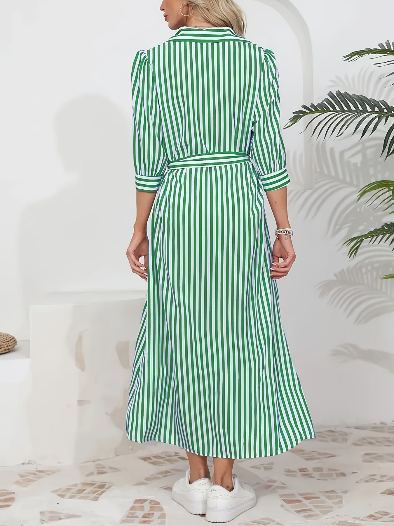 Woman wearing a striped poplin midi shirt dress with 3/4 sleeves, a collared neckline, and a tie waist, styled with white trainers.