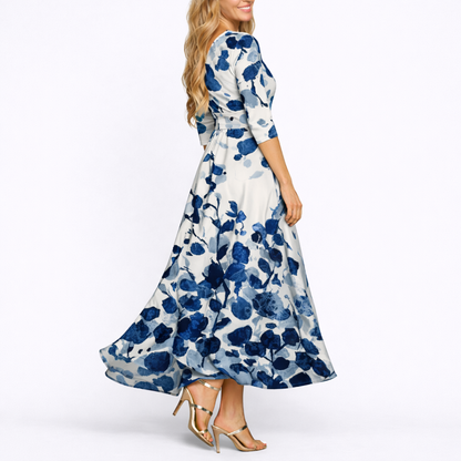 Blue & White - Woman wearing a long satin floral maxi dress with 3/4 sleeves, a V-neckline, and a sweeping A-line skirt.