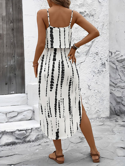 White - Model wearing a lightweight woven strappy midi dress with an abstract vertical pattern, adjustable waist tie, and side split, standing outdoors against a white textured wall.