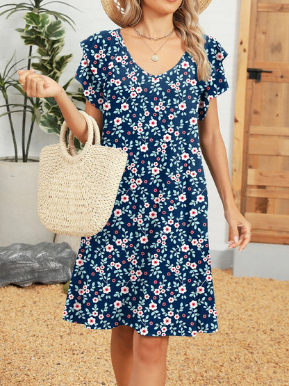 Blue - Woman wearing a lightweight woven animal-print shift dress with a V-neckline and short flutter sleeves, styled with a woven bag.