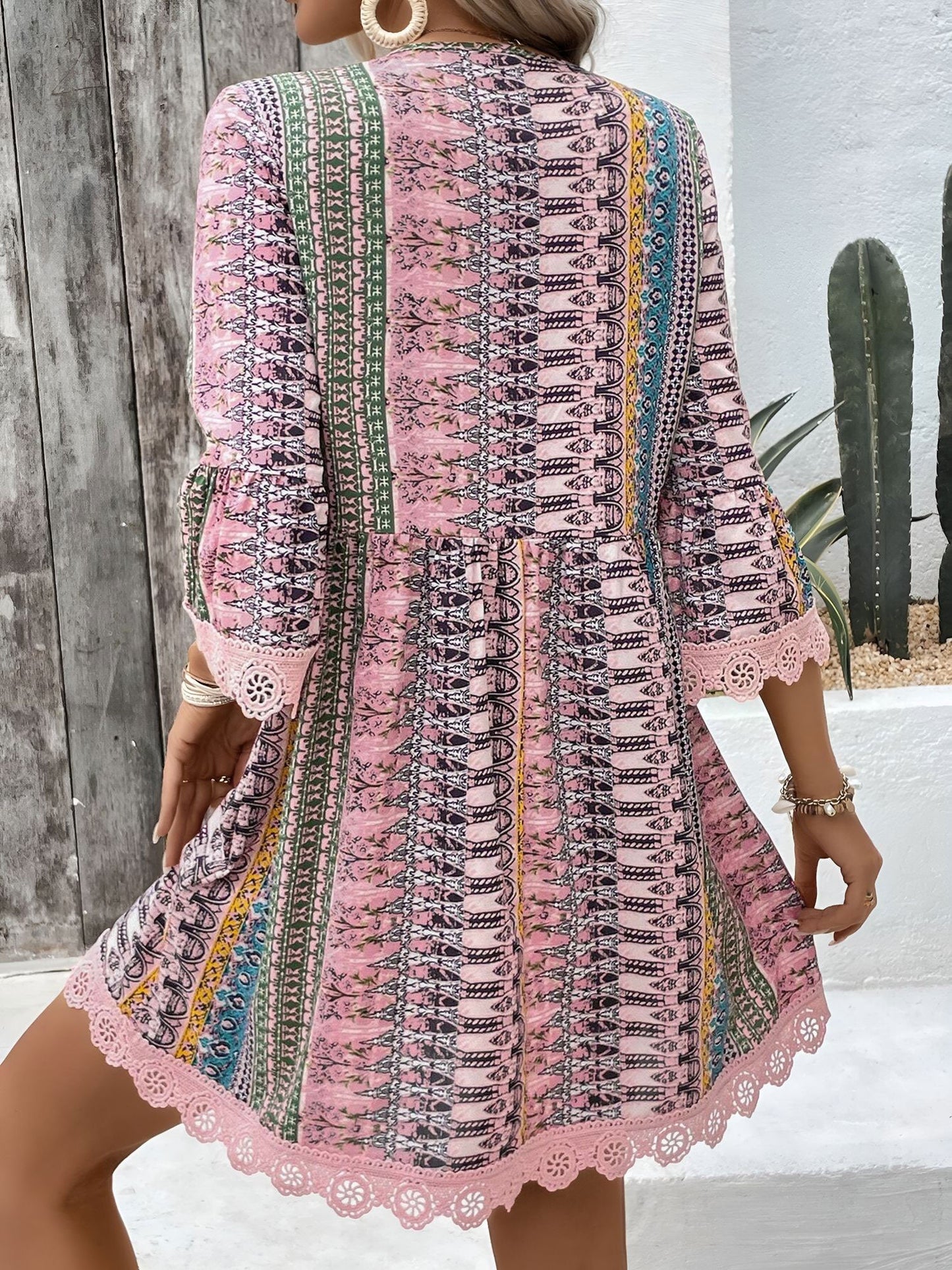 Pink - Woman wearing a patterned V-neck mini dress with 3/4 sleeves and lace trim detailing
