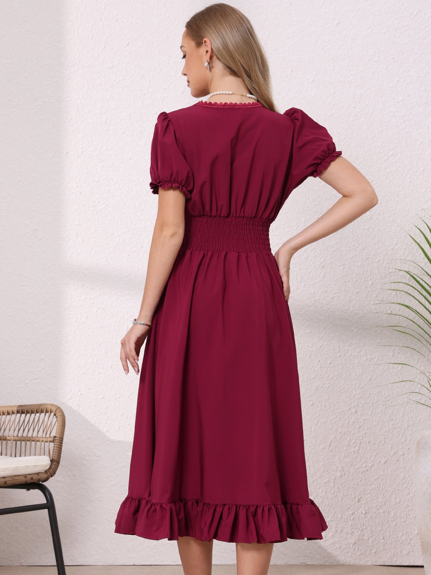 Burgundy - Model wearing a solid woven midi dress featuring a square neckline, short puff sleeves, a wide smocked waist, and a dramatic ruched front with an asymmetrical ruffled hem.