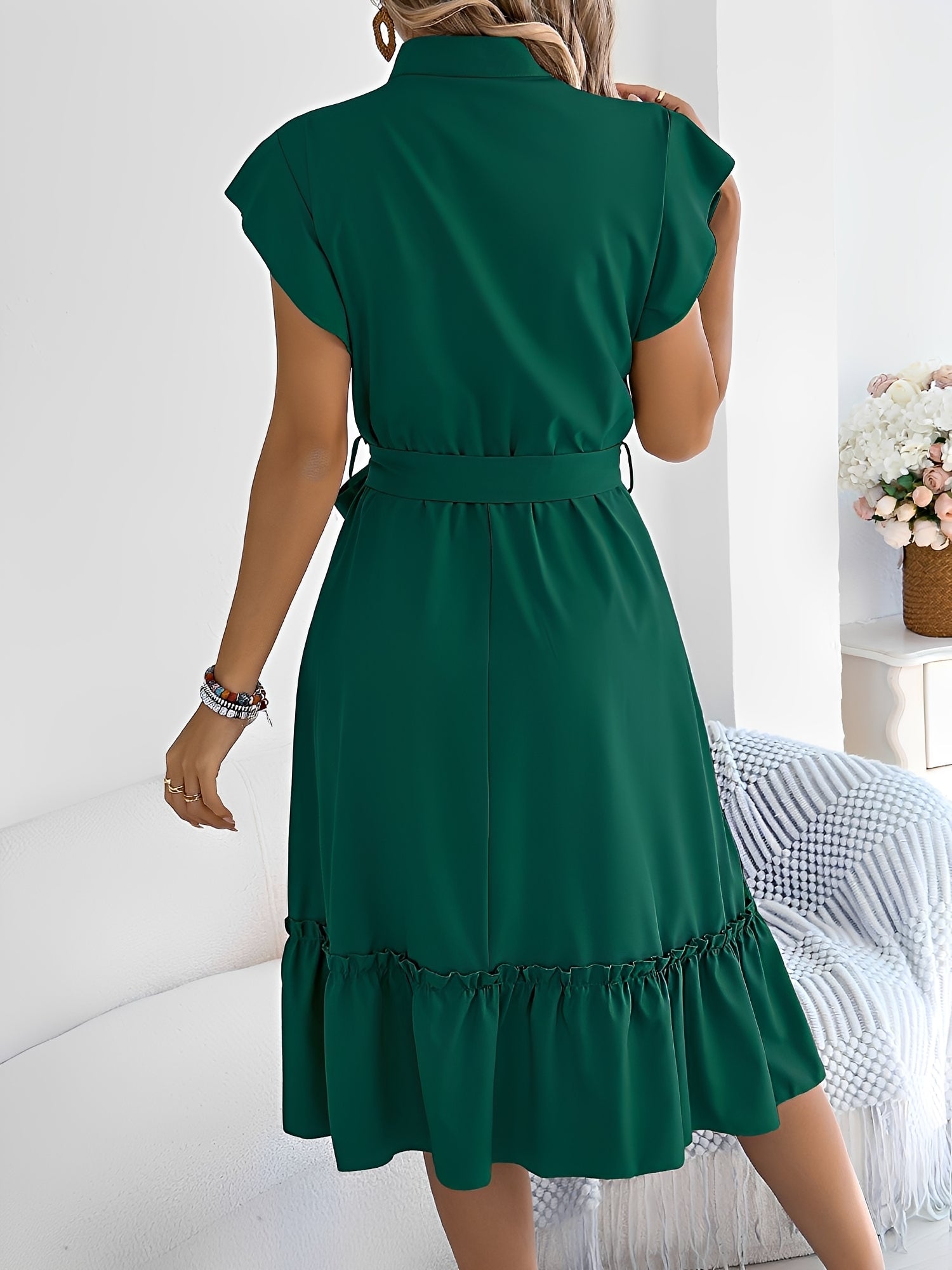 Green - A woman wearing a woven short-sleeve midi shirt dress with a collared neckline, button-down front, tie waist, and tiered ruffle hem, holding a woven bag.