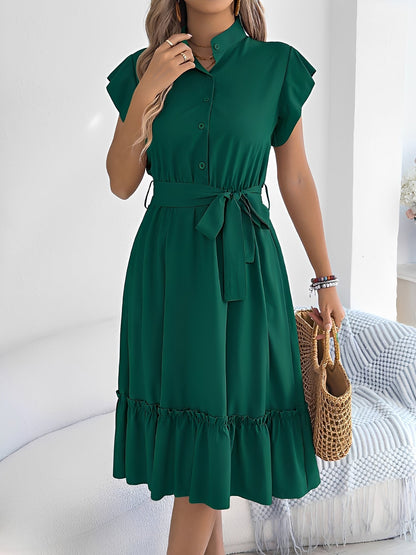Green - A woman wearing a woven short-sleeve midi shirt dress with a collared neckline, button-down front, tie waist, and tiered ruffle hem, holding a woven bag.