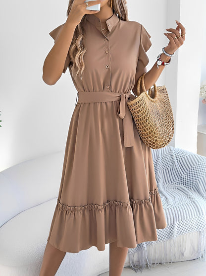 Khaki - A woman wearing a woven short-sleeve midi shirt dress with a collared neckline, button-down front, tie waist, and tiered ruffle hem, holding a woven bag.