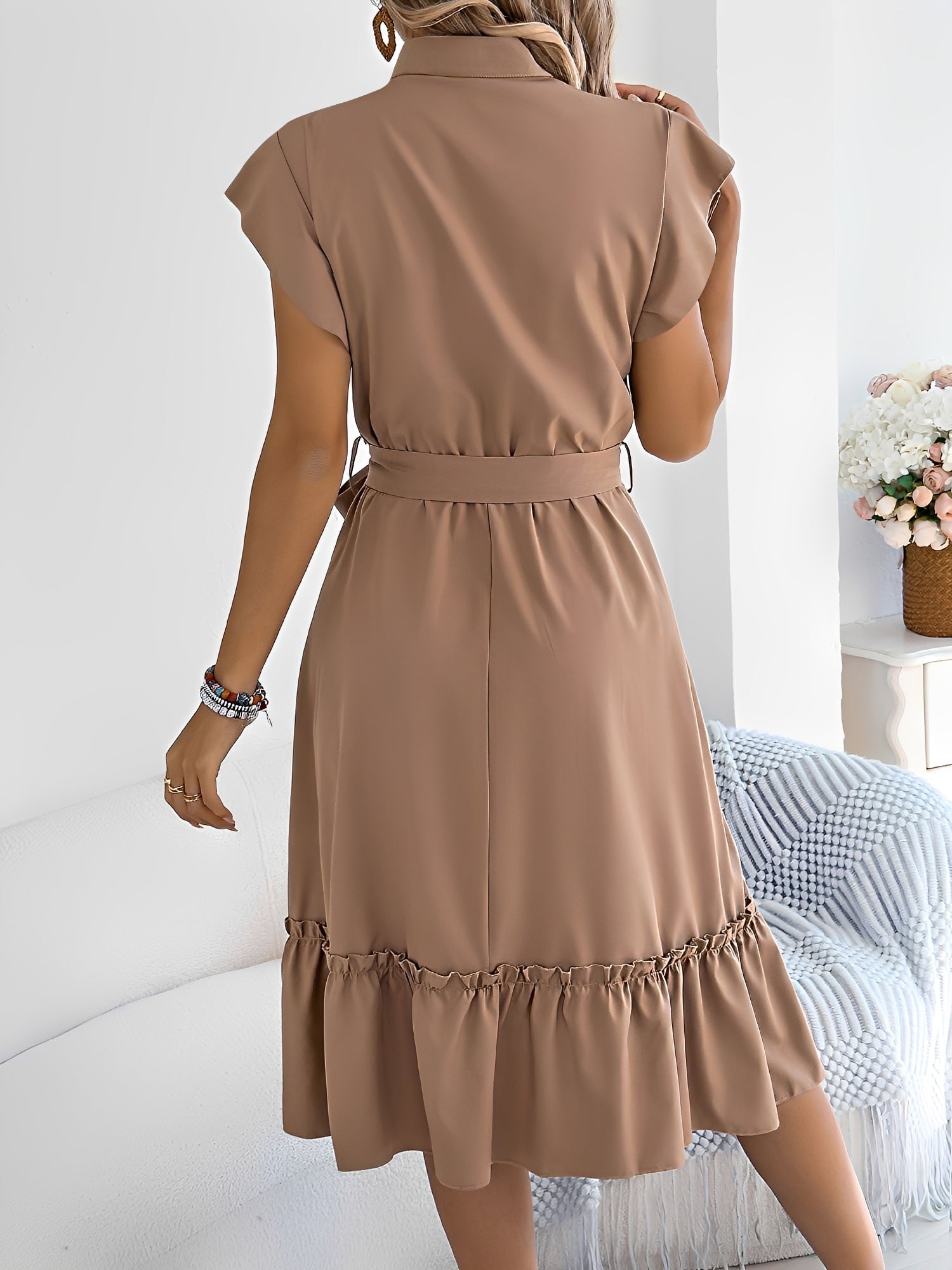 Khaki - A woman wearing a woven short-sleeve midi shirt dress with a collared neckline, button-down front, tie waist, and tiered ruffle hem, holding a woven bag.