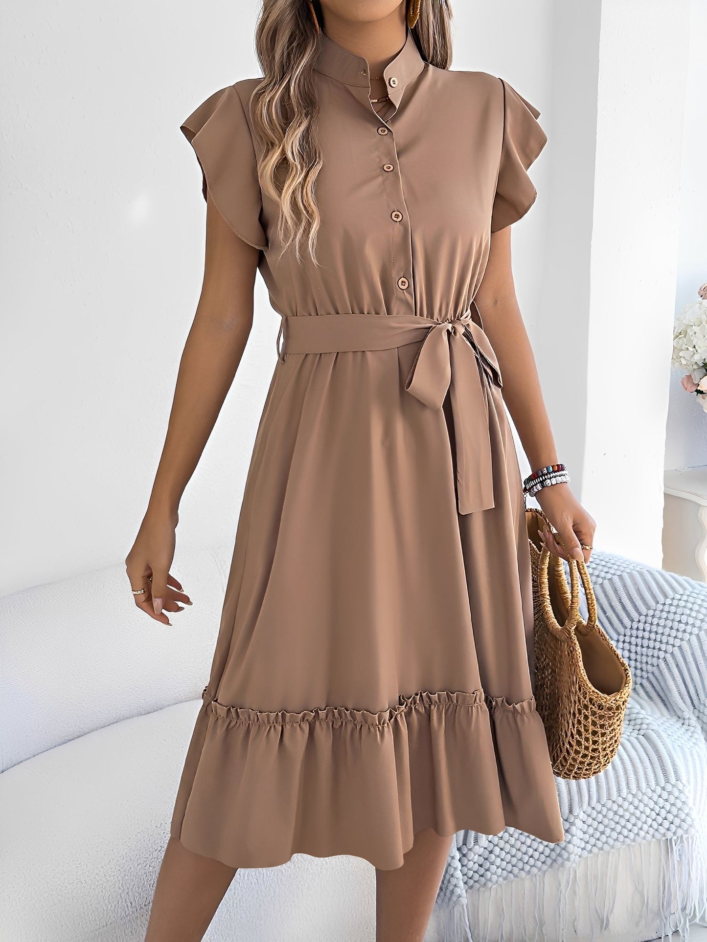 Khaki - A woman wearing a woven short-sleeve midi shirt dress with a collared neckline, button-down front, tie waist, and tiered ruffle hem, holding a woven bag.
