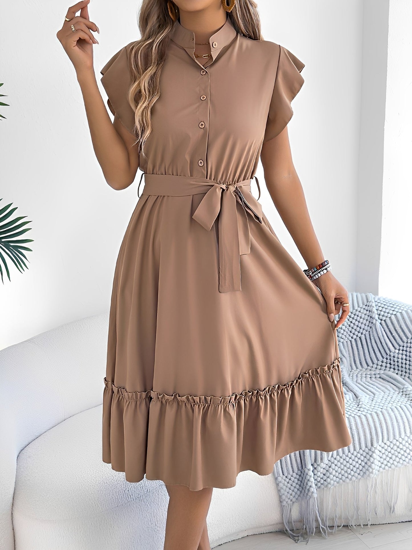 Khaki - A woman wearing a woven short-sleeve midi shirt dress with a collared neckline, button-down front, tie waist, and tiered ruffle hem, holding a woven bag.