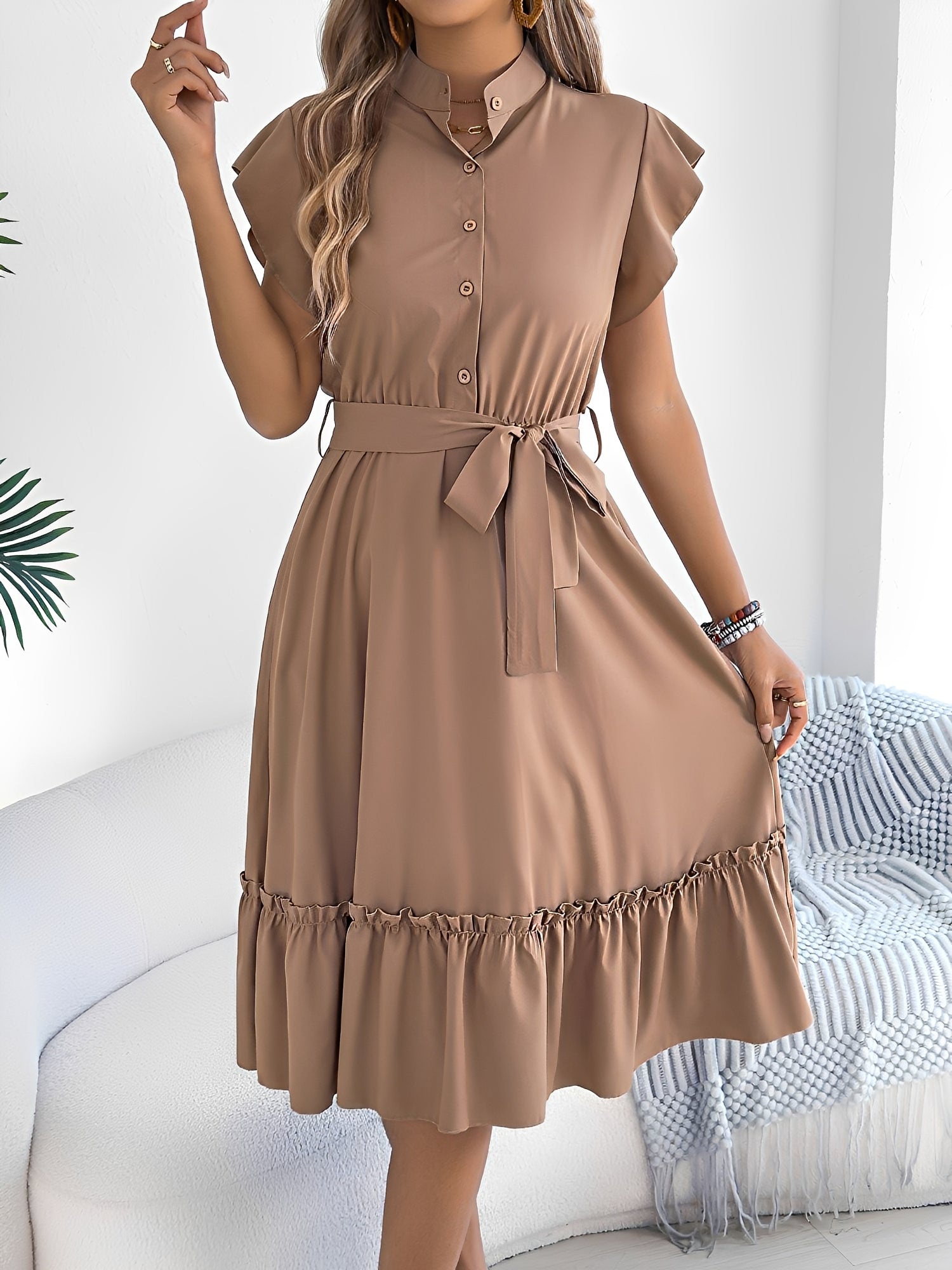 Khaki - A woman wearing a woven short-sleeve midi shirt dress with a collared neckline, button-down front, tie waist, and tiered ruffle hem, holding a woven bag.