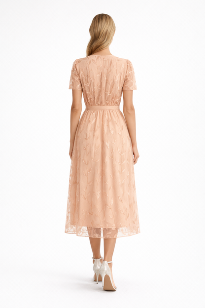 Peach - Woman wearing a woven wrap-style midi dress with short sheer sleeves, a tie waist, and a textured overlay, standing against a white background.